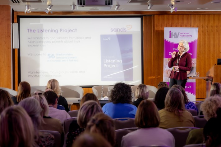 woman presenting to audience with a screen