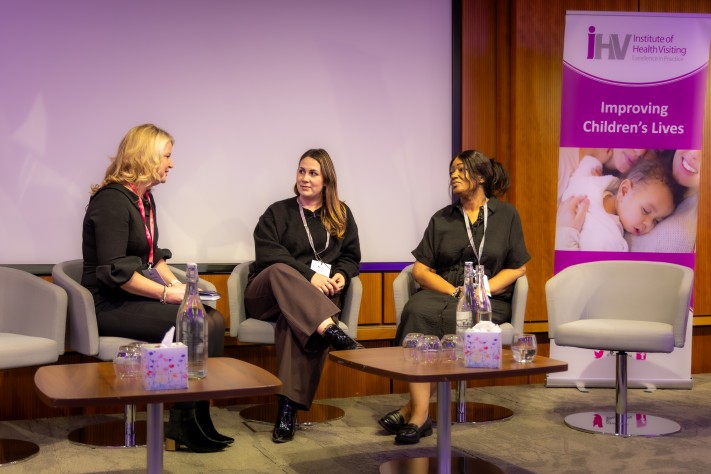3 women sat on chairs on a stage talking
