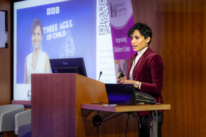 woman standing at lectern presenting at conference